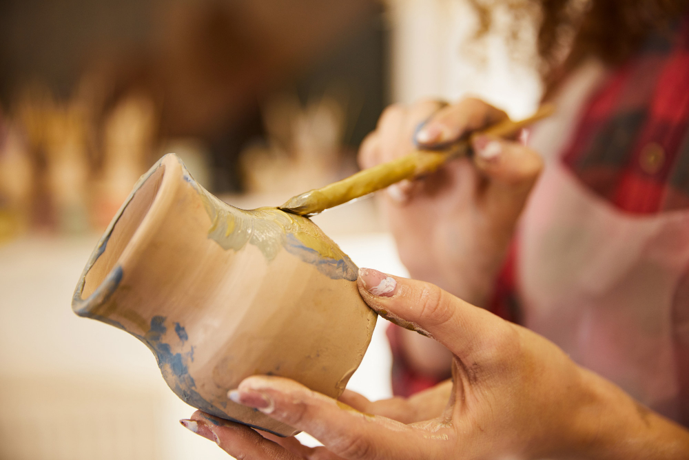 ženská ruka držiaca keramiku, maľovanie na malý hlinený džbánik